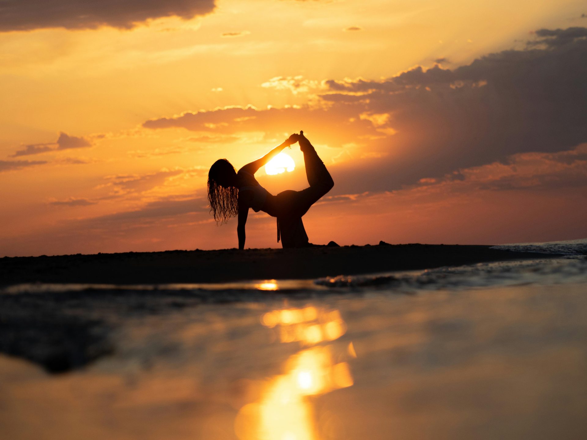 La silhouette sereine d'une femme pratiquant le yoga lors d'un magnifique coucher de soleil sur la plage.